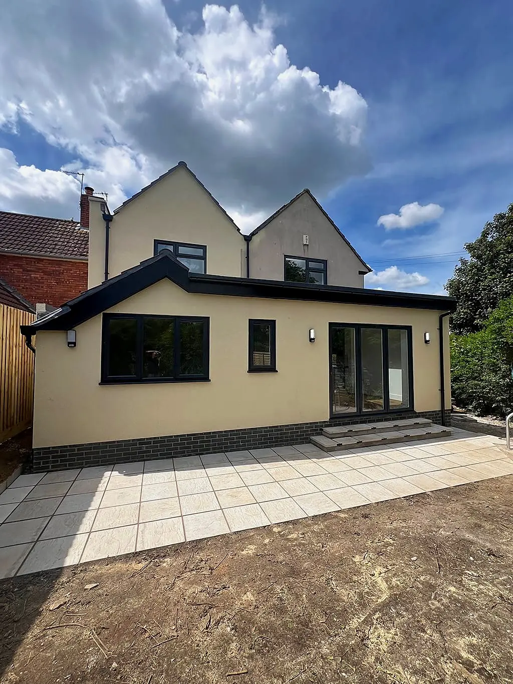 Rear extension in cream render with bifold doors opening to a patio